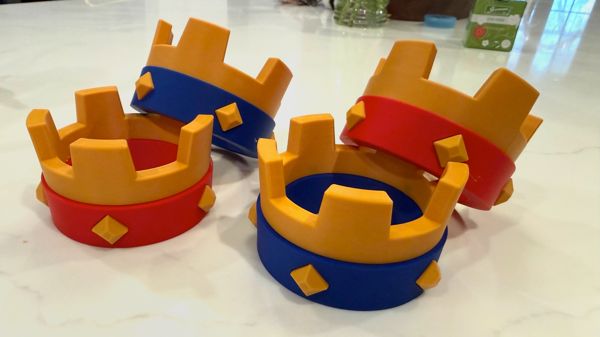 Four 3D printed Clash Royale crowns in gold, red, and blue sitting on a white marble surface