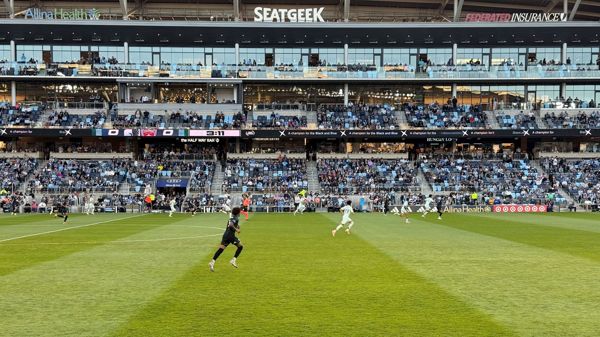 Soccer match at Allianz Field with players on the pitch and a packed crowd in the stands behind a SeatGeek sign.